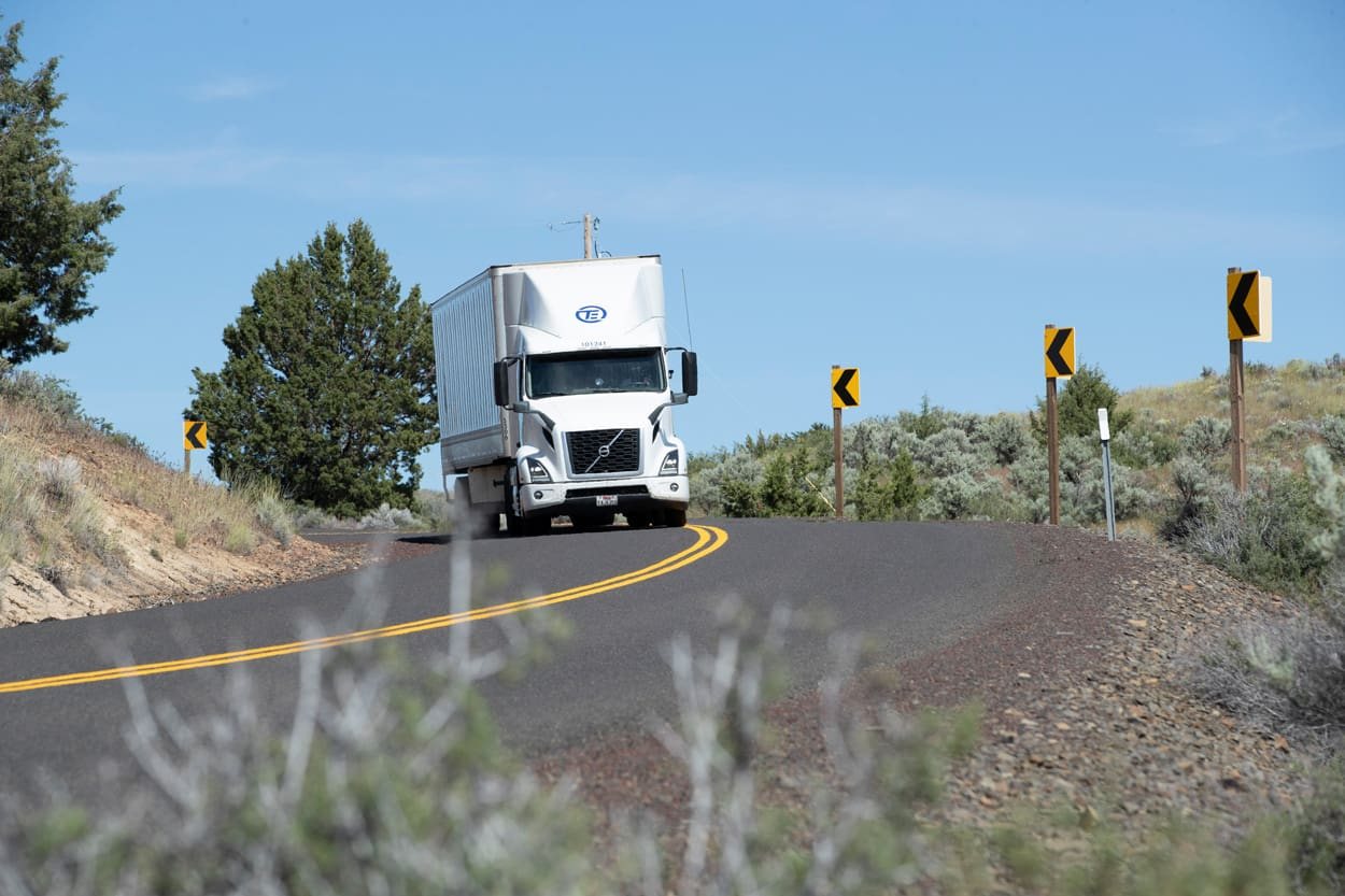 A semi truck driving along a winding highway